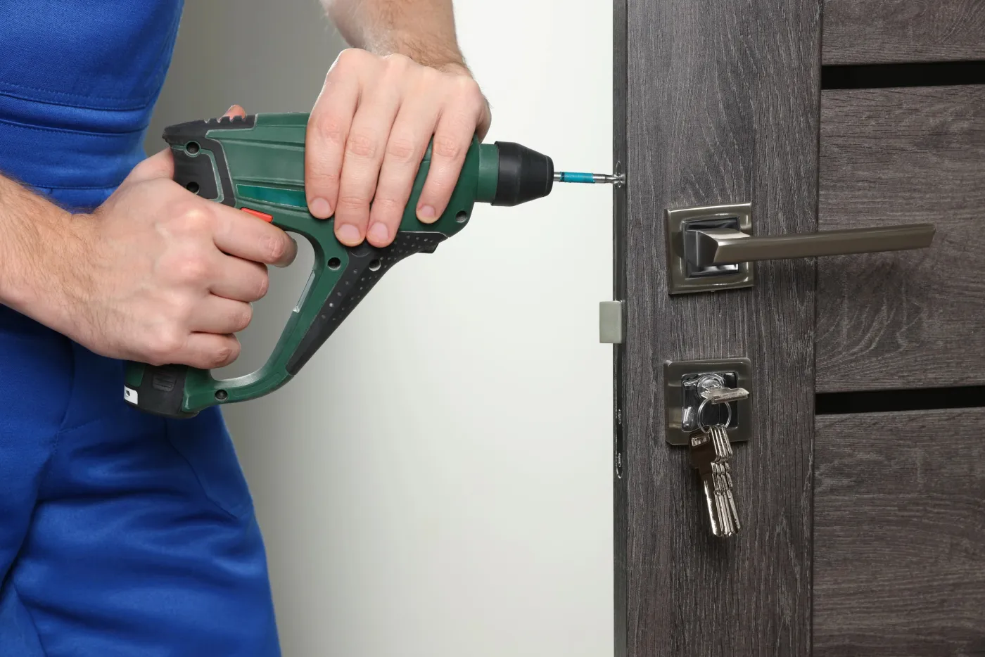 Serrurier vissant une serrure sur une porte d'entrée à Houilles